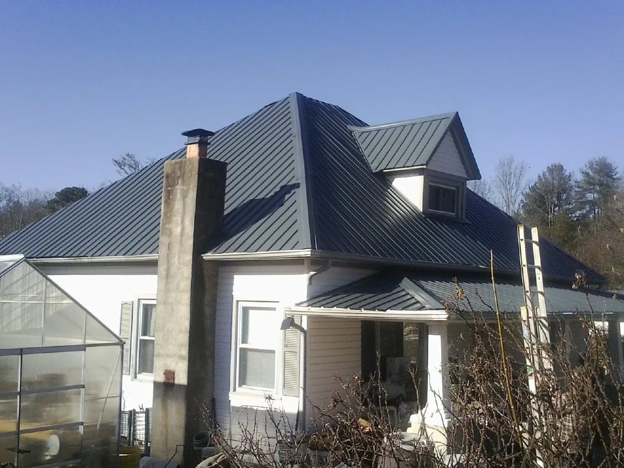Dark blue standing seam metal roof on a white farmhouse with dormer — Slate & Tile Roof Repair by Roofing Brothers in Peoria Heights