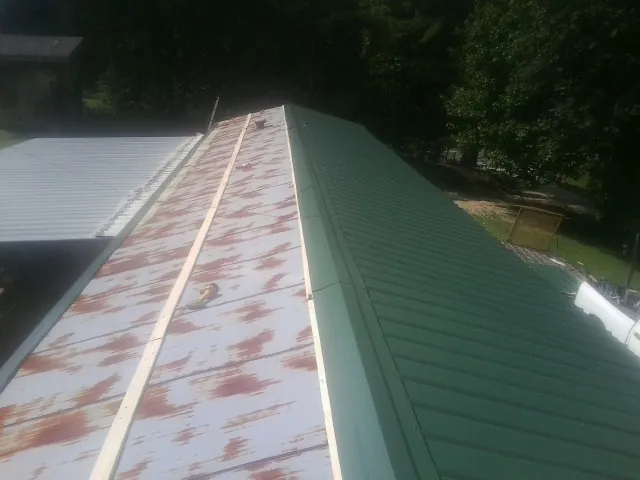 Old rusted panels beside newly installed green metal roofing — Wind Damage Roof Repair by Roofing Brothers in Peoria Heights