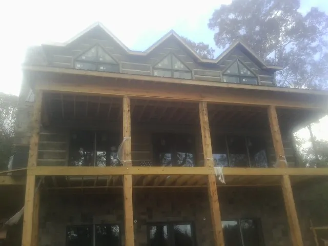 Dormers and porch framing on a large log home under construction — Roof Coating work by our crew in Peoria Heights