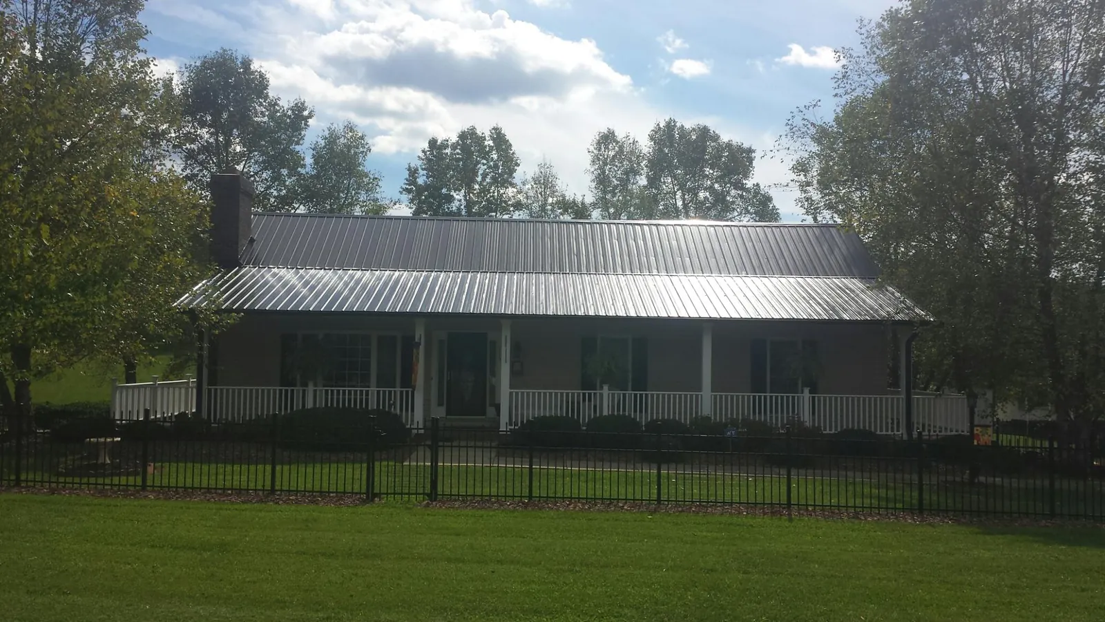 Gray metal roof on a brick ranch with a full width front porch — Gutter Guard Installation work by our crew in Peoria Heights