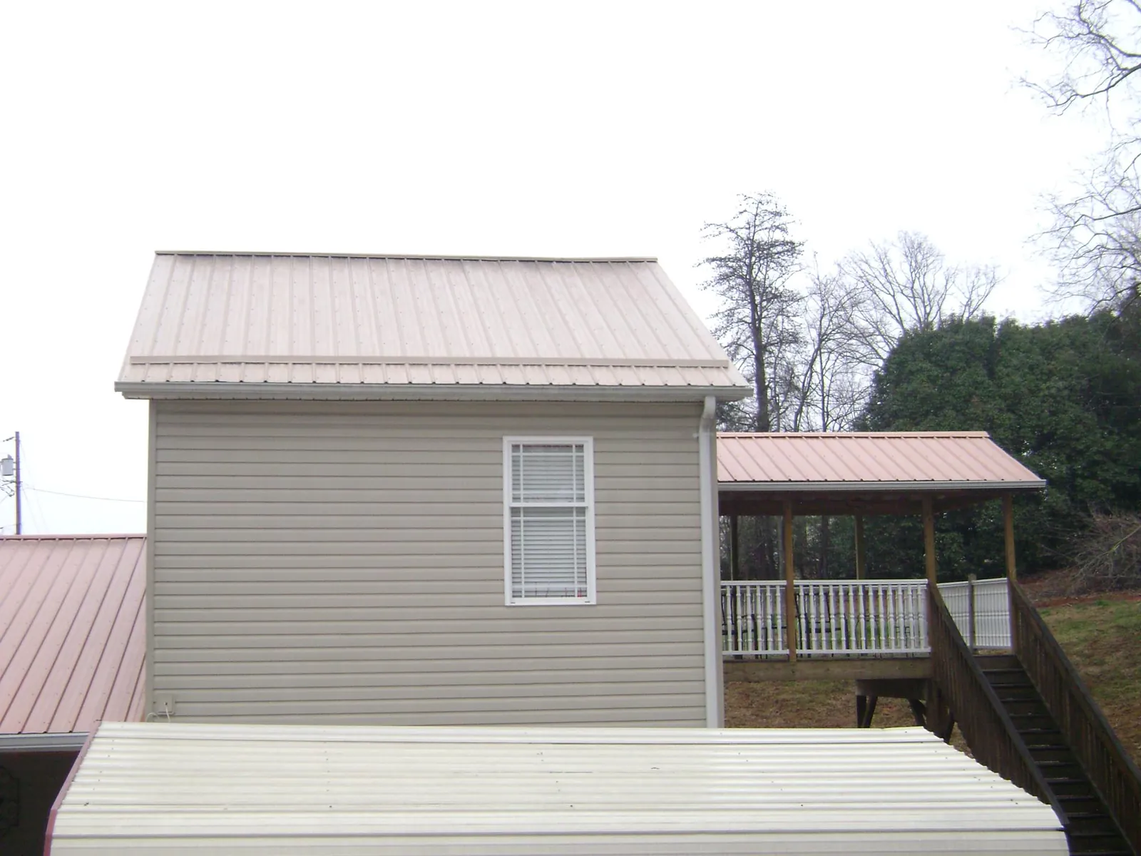 Tan metal roofs on a two story addition and attached porch, from a Roof Replacement job in Peoria Heights